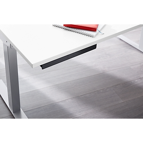 A white desk, shown partially from the front and diagonally from below. There is a notepad and red book on the table. Gray floor.