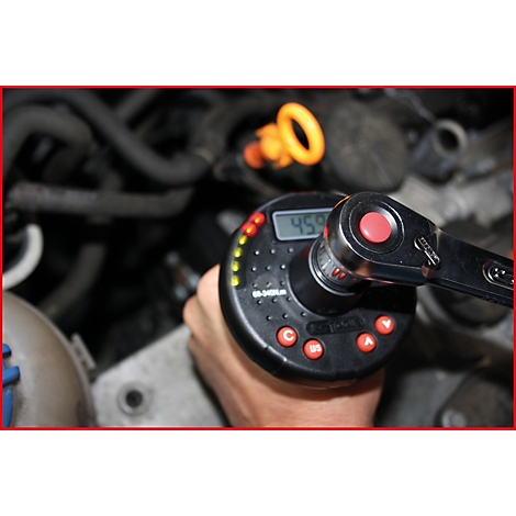 Mechaniker mit elektronischem Drehmomentschlüssel beim Schrauben in einem Motorraum. Auf dem Display ist 459 angezeigt.