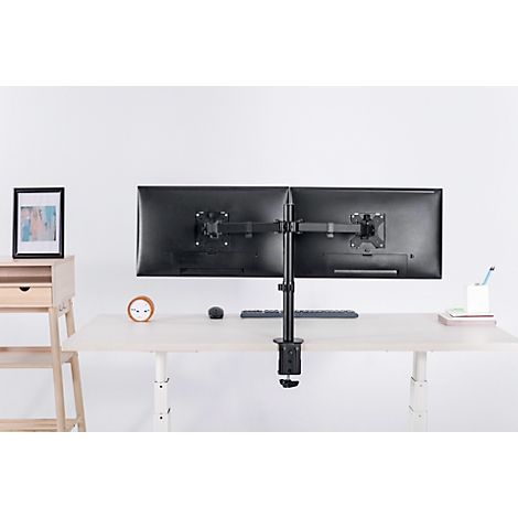 A black dual monitor mount on a white desk. More office supplies and a picture in the background.