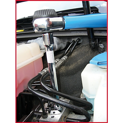 Blick in einen Motorraum. Ein Werkzeug wird verwendet, um an Rohren zu arbeiten.