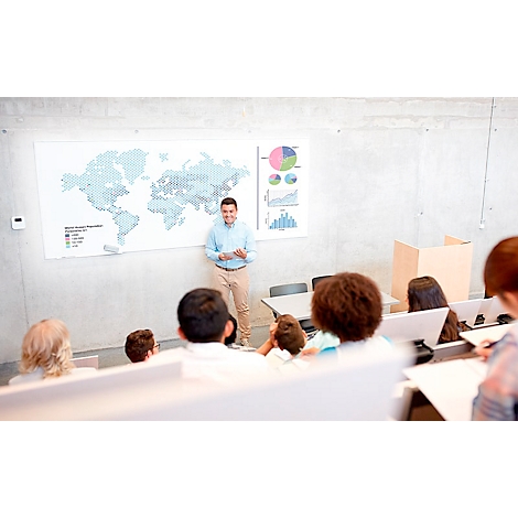 A man presents to a class. A world map and diagrams are visible on the wall. Students are listening attentively.