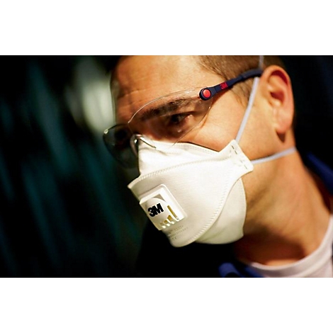 Gros plan d'un homme portant des lunettes de sécurité et un masque respiratoire. Le logo 3M est visible sur le masque.