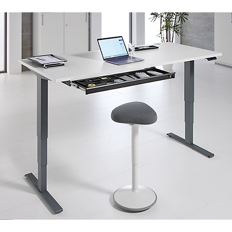 In hoogte verstelbaar bureau met laptop, lade en kruk. Andere items op de tafel.