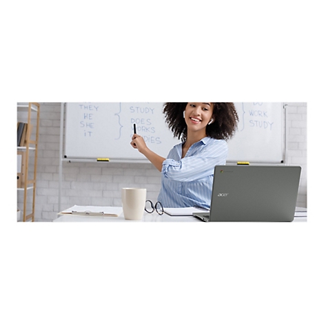 Eine afroamerikanische Frau unterrichtet vor einer Tafel Englisch. Sie lÃ¤chelt und zeigt auf das Wort does mit einem Stift. Vor ihr steht ein Laptop.