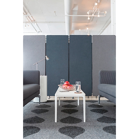 Two gray sofas and a low table in front of a partition. There are fruits and glasses on the table.