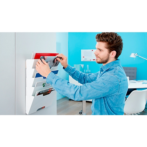 A man is putting a brochure into a white wall organizer.