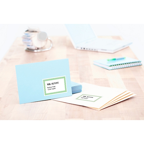 Lichtblauwe envelop met adressticker "Mr. Sunny" op houten tafel. Op de achtergrond: laptop en notitieboek.