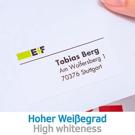 Lichtblauwe envelop met adreslabel, naast een witte envelop met label, laptop en notitieblok op een houten ondergrond.