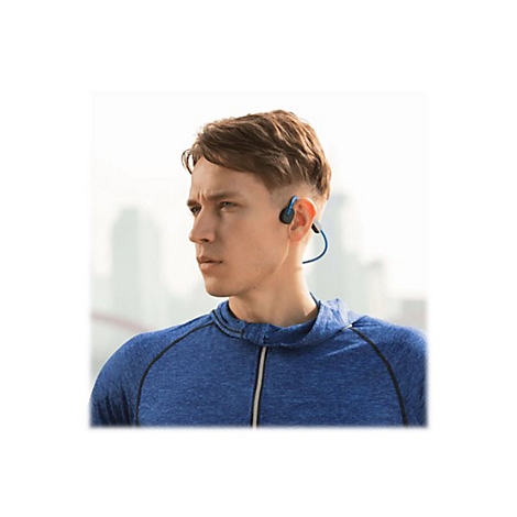 Junger Mann mit Bone Conduction KopfhÃ¶rern. Er trÃ¤gt ein blaues Sweatshirt und schaut zur Seite.