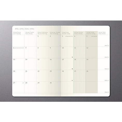 Un carnet ouvert avec un calendrier mensuel pour avril. Pages beiges, fond gris. Les numéros de semaine sont à droite.