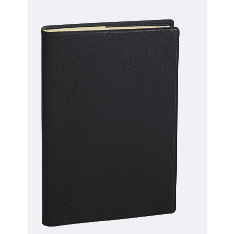 Livre en cuir noir, légèrement ouvert, sur fond clair.
