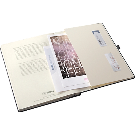Carnet noir ouvert avec du papier dans la poche intérieure. Des textes et des logos sont visibles sur le papier.