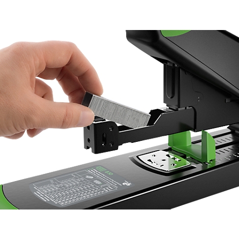 Gros plan d'une main chargeant des agrafes dans une agrafeuse noire et verte.