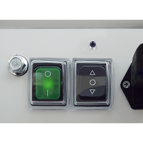 Close-up of two illuminated switches and a screw on a white surface. One green switch is lit, a black one shows arrow symbols.