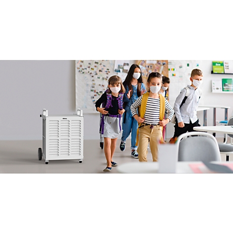 Schoolchildren with masks leaving a classroom. In the foreground is a white air purifier.