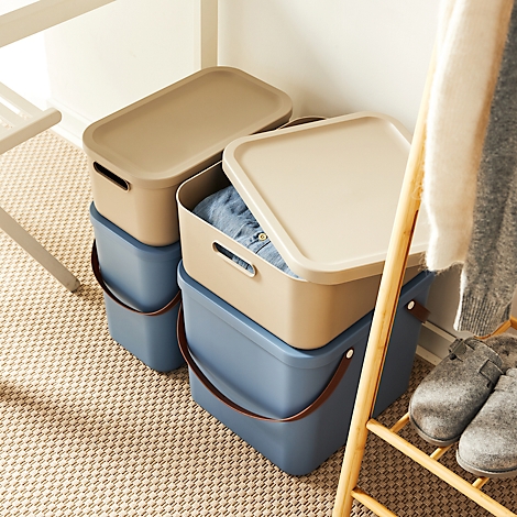 Blue and beige storage boxes, partially open. Clothes and slippers lie on a stool.