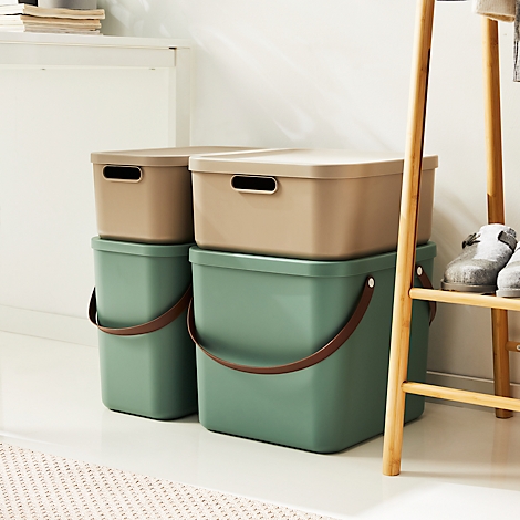 Two green storage boxes with brown handles and lids. Behind them, a wooden stand.