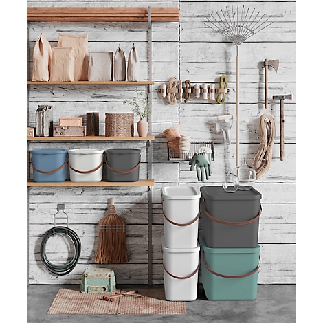 A well-organized garage with shelves, buckets, and tools, including a rake and a broom.