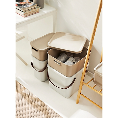 Several stackable storage boxes in beige and white with handles. One box is open and contains textiles.