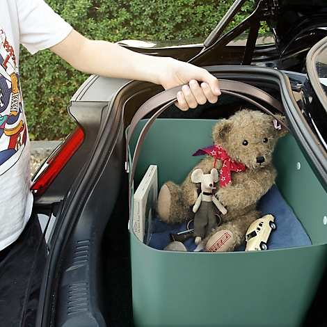 Person lifting a basket full of toys out of the trunk of a car.