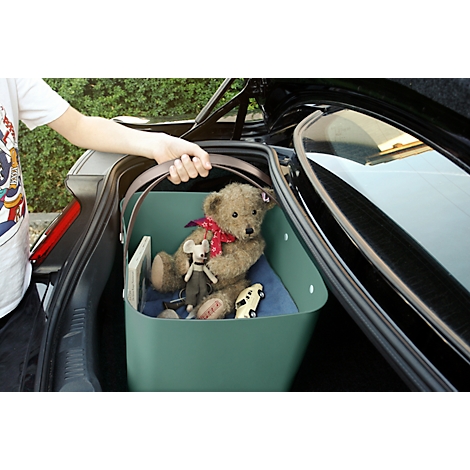 Person lifting a green box with teddy bear and toys out of the trunk.