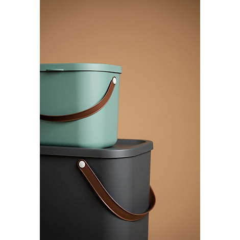 Two waste bins. A turquoise bin is on top of a grey one. Both have brown handles.