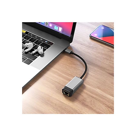 Ein grauer Ethernet-Adapter steckt in einem Laptop auf einem Holztisch.