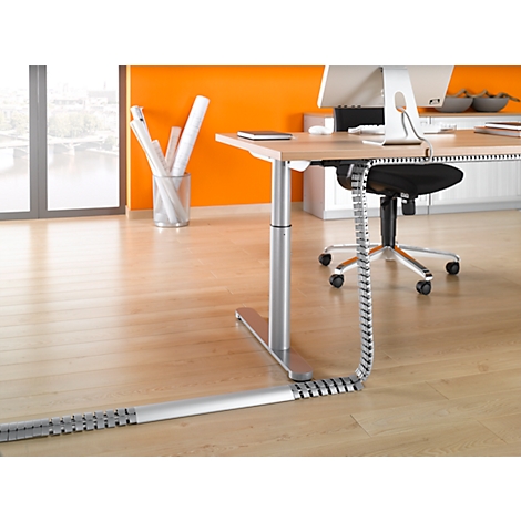 Office desk with cable management. View into an office, with wooden floor, orange wall and large windows.