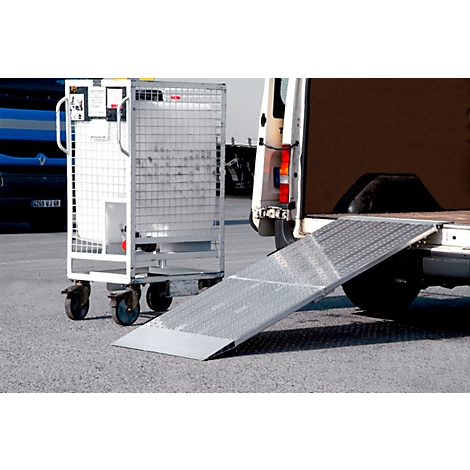 Grey roll cage next to an extended loading ramp of a delivery van.