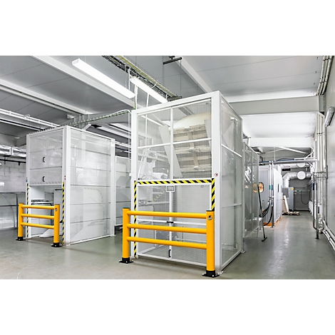 Industriehal met witte veiligheidskooien en gele afzettingen. Op de achtergrond buizen en ventilatie.