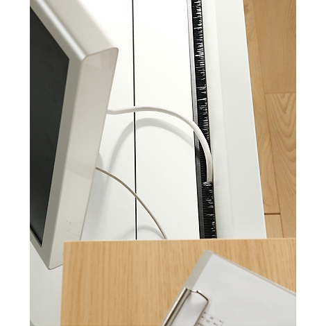 Close-up of a white monitor with cables, next to a ruler and a file folder.