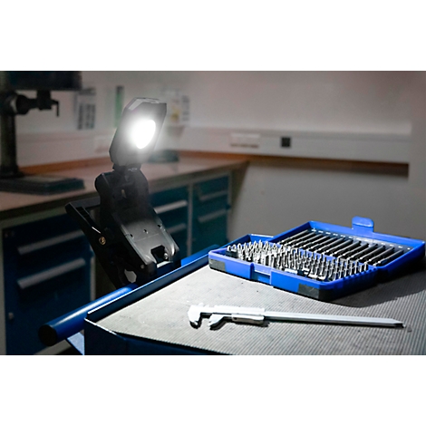 Gereedschapskist met opzetstukken, schuifmaat en werklamp op een tafel.