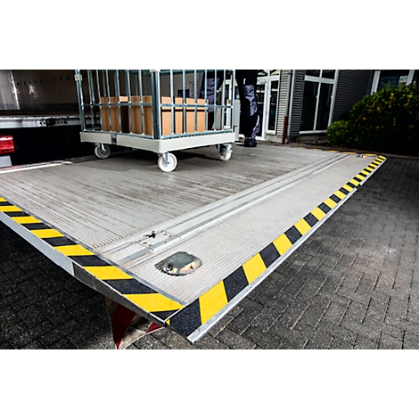 Loading ramp with trolley and boxes. Yellow and black markings on the edge.