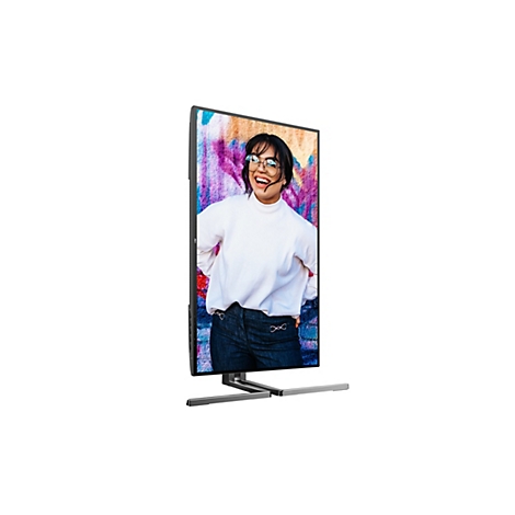 Ein Monitor, auf dem eine junge Frau mit Brille vor einem Graffiti-Hintergrund abgebildet ist.