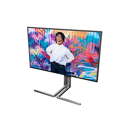 Ein großer Monitor zeigt eine Frau mit Brille, die vor einer Graffiti-Wand lächelt. Der Monitor steht auf einem modernen Metallfuß.
