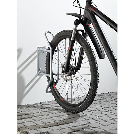 Una bicicleta de montaña negra en un soporte de pared. La rueda delantera de la bicicleta es visible.