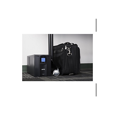 Ein schwarzes APC Smart-UPS C1000 steht neben einer schwarzen Aktentasche und einem Stuhl. Auf dem UPS-Display werden Zahlen angezeigt.