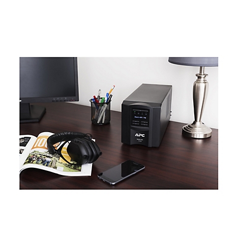 Ein schwarzes APC-USV-GerÃ¤t steht auf einem Schreibtisch neben einem Monitor, KopfhÃ¶rern und einem Smartphone.