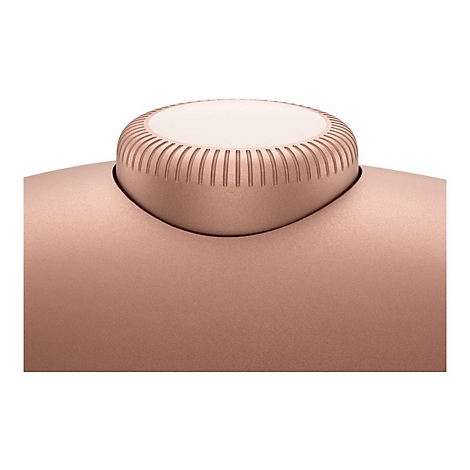 Gros plan d'un écouteur en or rose, avec un capuchon rond et rainuré avec un centre plus clair.