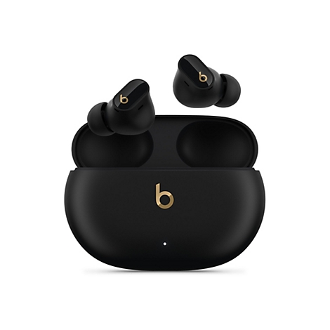 Écouteurs Beats noirs avec logo 'b' doré, seuls, dans un étui de chargement ouvert et à proximité sur fond blanc.