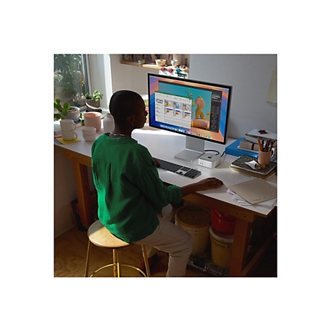 Person sitzt vor einem Computer, der in einem Arbeitszimmer steht. Der Bildschirm zeigt eine farbenfrohe OberflÃ¤che.
