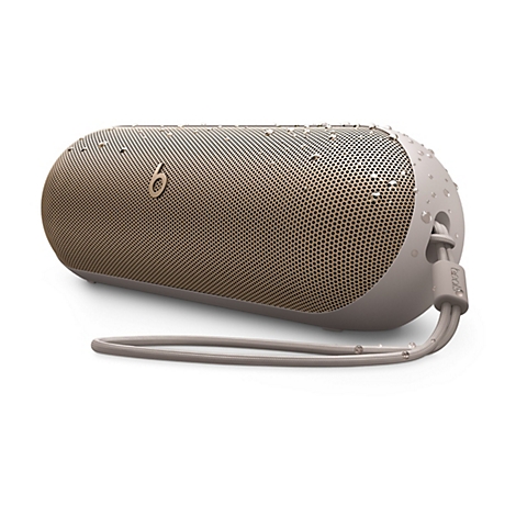 Enceinte Beats Pill+ beige sur fond blanc. Avec une sangle de transport et des gouttelettes d'eau.
