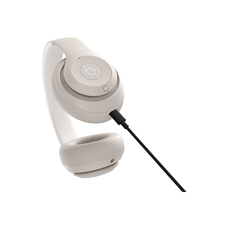 Beige Kopfhörer mit schwarzem Kabel, isoliert auf weißem Hintergrund. Das Beats-Logo ist sichtbar.