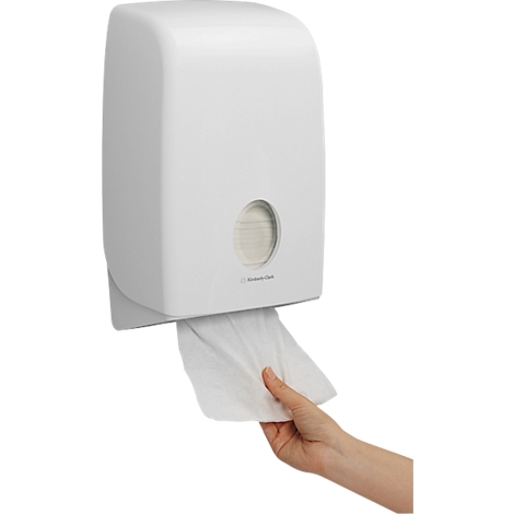 Weisse Handtuchspendebox, eine Hand entnimmt Papier. Auf der Box steht 'Rubbermaid'.