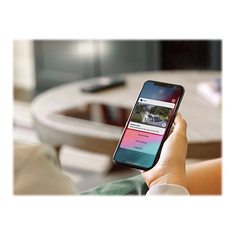 Eine Hand hält ein Smartphone mit einer Benachrichtigung, die eine Bewegungserkennung an der Haustür anzeigt.