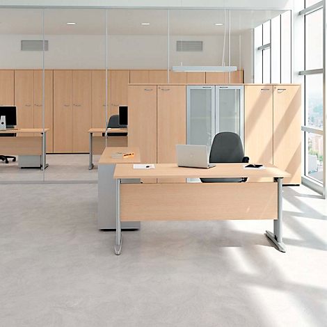 Office with wooden desks, chairs, cabinets, and a laptop. Bright, modern setting with large windows.