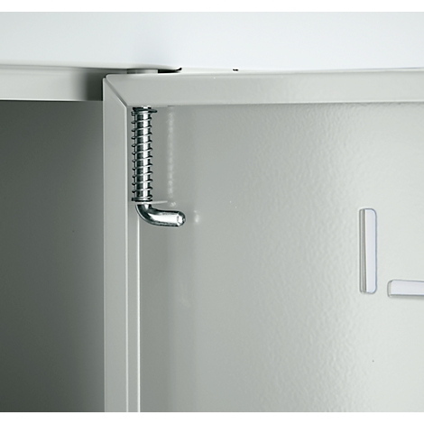 Primer plano de una bisagra de puerta de armario con resorte. La puerta es gris claro, la bisagra metálica.