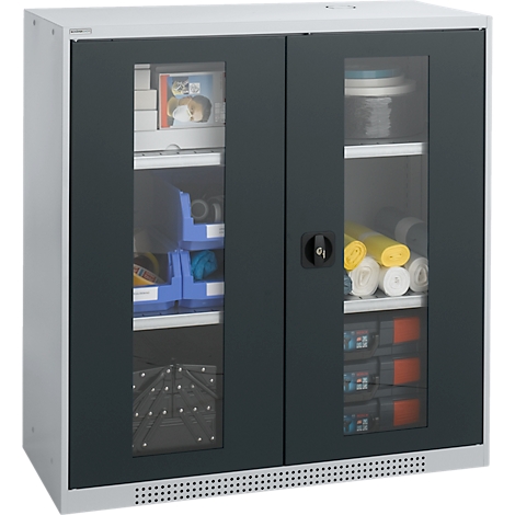 Armario gris con puertas de cristal, lleno de herramientas y materiales. Puertas negras, marco plateado, manija negra.