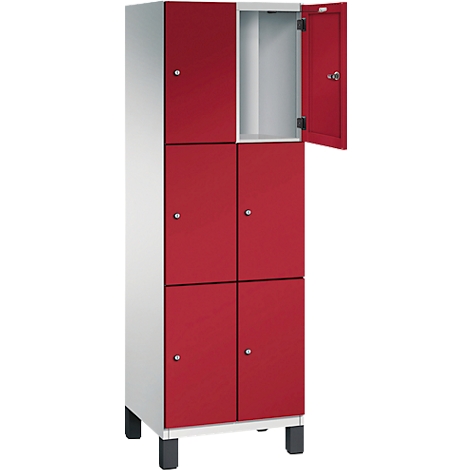 Une armoire avec des portes rouges, une porte ouverte, des poignées argentées et des pieds noirs.