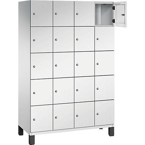 Armoire blanche avec 16 compartiments. Une porte est ouverte, à l'intérieur se trouve une étagère. Pieds noirs.